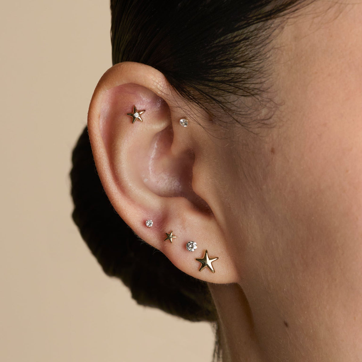 Worn shot of three gold lobe ear jewellery